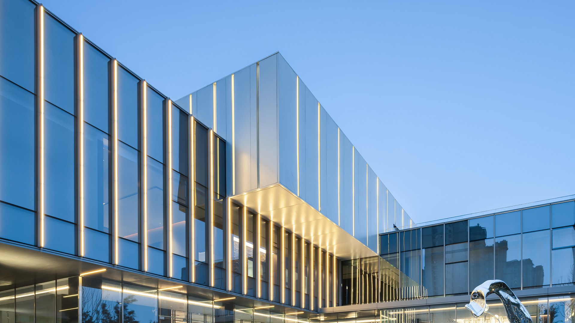 Modern glass facade with vertical metal fins and entrance glazing