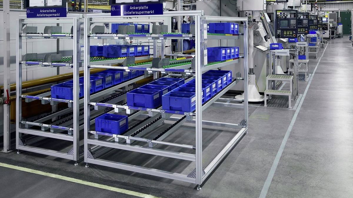 Aluminum profile flow racks with parts bins beside an industrial production line